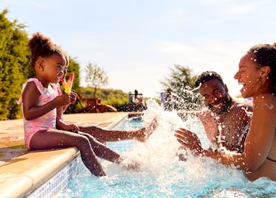 Family with small children splashes in pool together