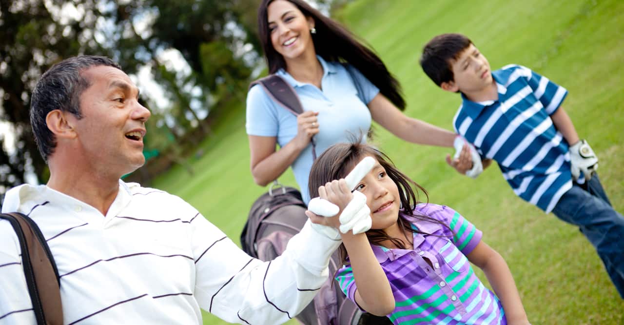 Family of four getting ready to play golf on a golf course. 